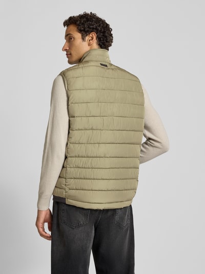 Männermodel trägt Steppweste mit Stehkragen und Eingrifftaschen von Christian Berg Men, beige, strukturierte Oberfläche, Ganzkörperansicht Rückansicht. Regular Fit, Reißverschluss, Rückenlänge 70 cm, Schulterbreite 44 cm, Brustweite 58 cm.