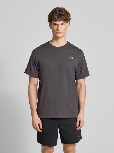 Männermodel trägt Relaxed Fit T-Shirt aus reiner Baumwolle von The North Face in anthrazit mit Rundhalsausschnitt und Label-Print, ganzkörperansicht von vorne.