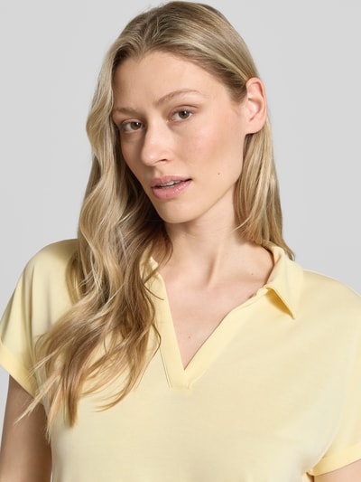 Frauenmodel trägt Regular Fit Poloshirt aus Modal-Mix von Christian Berg Woman in Gelb mit V-Ausschnitt und Aufschlag an den Ärmeln, Nahaufnahme Oberkörper. Rückenlänge bei Größe S: 46 cm.