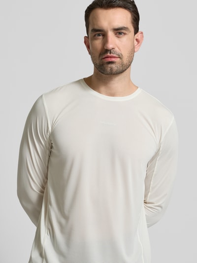 Männermodel trägt Funktionsshirt mit Logo und Rundhalsausschnitt von Salomon in Creme, Regular-Fit, Langarmshirt, Rückenlänge 69 cm bei Größe M, Nahaufnahme Oberkörper.