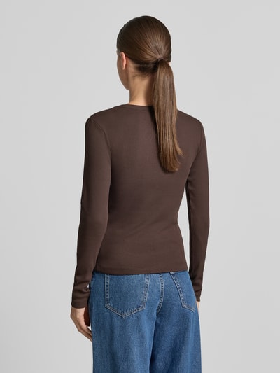 Frauenmodel trägt braunes Slim Fit Langarmshirt aus Baumwoll-Mix Modell 'CHLOE' von VERO MODA, kombiniert mit blauen Jeans, Ganzkörperansicht Rückansicht.