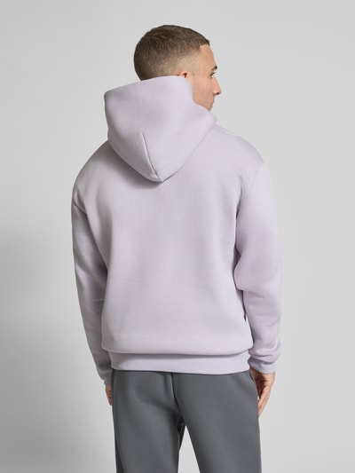 Männermodel trägt Hoodie mit Känguru-Tasche von REVIEW in hellem Flieder, lockere Passform, Baumwollmischung, Rückenansicht, Ganzkörperansicht.
