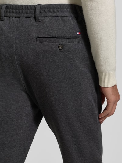 Männermodel trägt Relaxed Fit Schmale Hose aus reiner Baumwolle Modell 'HARLEM' van Tommy Hilfiger, uni two tone, label stitching, regular lengte, elastische tailleband, achterzakken, detailopname rug.