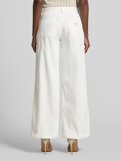 Männermodel trägt Wide Leg Jeans mit Paspeltaschen Modell 'ZOYA' von Guess aus bawełna, kolor biały, lamowane kieszenie, Ganzkörperansicht Rückansicht. Szerokość w rozmiarze 27/32: 37 cm, długość wewnętrzna nogawki: 77 cm.