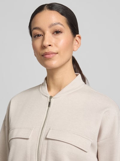 Modelka kobieca ma na sobie Piqué Blouson Jacke mit Taschen od Christian Berg Woman w kolorze jasnobeżowym, materiał z bawełną, proste kroje, piqué, kieszenie z patkami, stójka, zamek, elastyczne mankiety, opadające ramiona, zbliżenie na górną część ciała