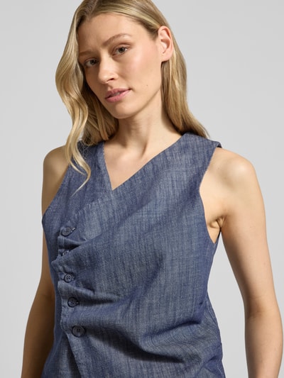Vrouwenmodel draagt bodywarmer van puur katoen met V-hals, knoopsluiting, regular fit, model 'DAZZIE' van My Essential Wardrobe, borstwijdte 46 cm, ruglengte 50 cm, schouderbreedte 32 cm, maat 36, blauwe textuur, close-up bovenlichaam.