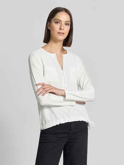 Frauenmodel trägt Regular Fit Bluse mit Brusttaschen von monari, Weiß, Ziersteinbesatz, Tunika-Ausschnitt, Langarm, Ganzkörperansicht von vorne.