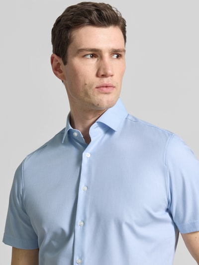 Męski model nosi Slim Fit Business-Hemd in kurzärmligem Design Modell 'Modern' von OLYMP Level Five, jasnoniebieski, materiał bawełniany ze streczem, kent kołnierz, krótki rękaw, krój slim fit, długość pleców w rozmiarze 40: 79 cm, szerokość w rozmiarze 40: 43 cm, długość rękawa w rozmiarze 40: 24 cm, gładka tekstura, zbliżenie na górną część ciała