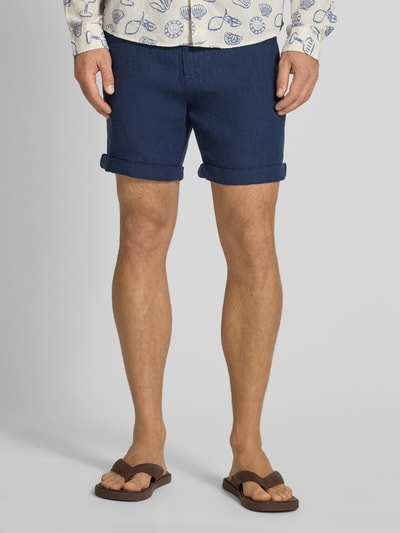 Mężczyzna nosi Leinenshorts mit Bindegürtel und Gesäßtaschen von MCNEAL, granatowy len, krój straight fit, zapięcie na guzik i zamek błyskawiczny, wiązany pasek, wpuszczane kieszenie, podwijane nogawki, z tyłu kieszenie z wypustką na guzik, wyhaftowane logo z tyłu, szerokość w rozmiarze M: 45 cm, długość wewnętrzna nogawki w rozmiarze M: 16 cm, zdjęcie: widok całej sylwetki z przodu.