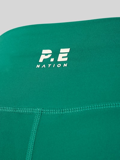 Produktfoto, grüne Slim Fit Leggins mit Logo-Print Modell 'Dynamic' von P.E Nation, elastischer Bund, glatte Oberfläche, Detailaufnahme.