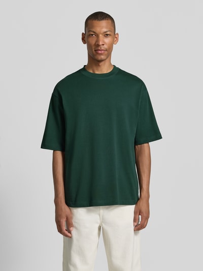 Męskimodel nosi zielony t-shirt Regular Fit T-Shirt aus reiner Baumwolle Modell 'HASPEN' von SELECTED HOMME, gładka textura, Ganzkörperansicht von vorne.