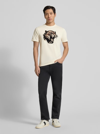Męski model nosi Regular Fit T-Shirt mit Motiv-Print od Antony Morato, mieszanka bawełny, krój regular fit, nadruk z motywem, okrągły dekolt, długość tyłu w rozmiarze M: 64 cm, jasne kolory, proste linie, gładka faktura, całkowity widok z przodu.