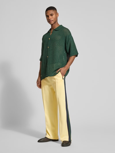 Männermodel trägt Trackpants mit Galonstreifen von ANOTHER COTTON LAB in Gelb mit dunklem Seitenstreifen, Relaxed Fit, Ganzkörperansicht von vorne.
