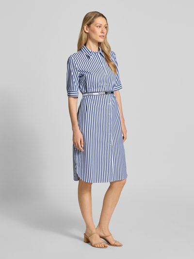 Modelka kobieca nosi Hemdblusenkleid mit Gürtel Modell 'Dominique2' od JOOP!, biało-niebieskie paski, krój slim fit, bawełna z domieszką stretchu, długość midi, kent kołnierzyk, pasek, zapięcie na guziki, 1/2 rękawa, długość tyłu w rozmiarze 36: 100 cm, szerokość w rozmiarze 36: 43 cm, długość rękawa w rozmiarze 36: 31 cm, widok całofigurowy z przodu.