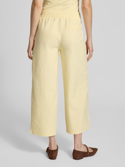 Frauenmodel trägt Hose in verkürzter Passform Modell 'KATE' von ICHI, hellgelb, Baumwoll-Mix mit Stretch, elastischer Bund, Ganzkörperansicht Rückansicht.