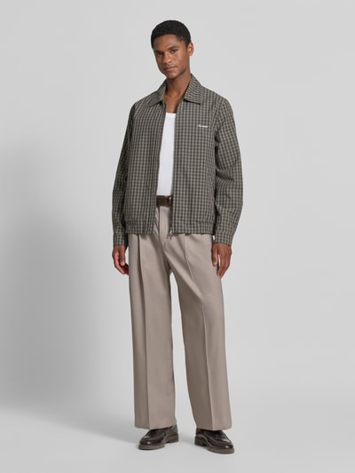 Männermodel trägt Wide Fit Hose mit Bügelfalten von Drykorn aus Baumwoll-Mix mit Stretch-Anteil, Beige, Ganzkörperansicht von vorne.