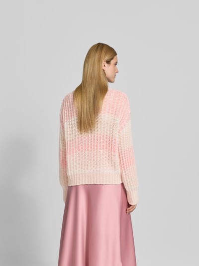 Frauenmodel trägt Relaxed Fit Pullover mit Alpaka-Anteil von Juvia in Strick-Optik und Lochmuster, zartrosa Töne, Ganzkörperansicht Rückansicht.