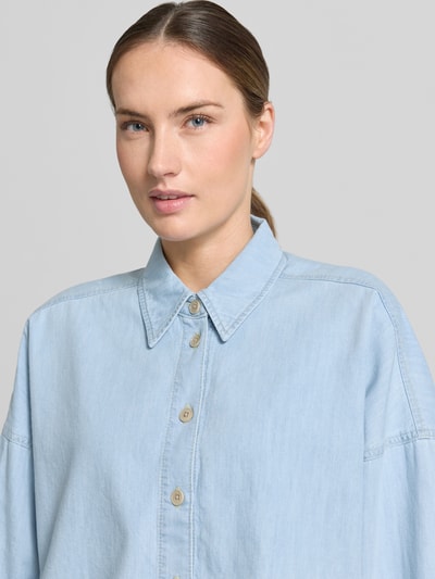 Frauenmodel trägt Relaxed-Fit Damen Hemdbluse in Denim-Optik Modell 'Oshia' von Drykorn aus Reine Baumwolle, Nahaufnahme Oberkörper.