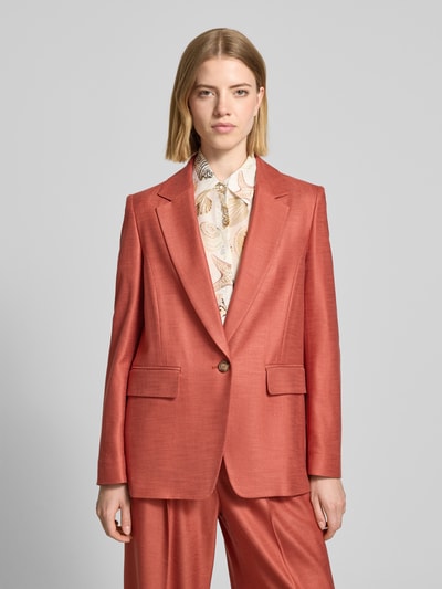 Frauenmodel trägt Slim Fit Blazer aus Viskose-Elasthan-Mix mit Pattentaschen von Marc Cain in Ziegelrot, Reverskragen, Knopfverschluss, Ganzkörperansicht von vorne, Rückenlänge 68 cm, Brustweite 49 cm, Ärmellänge 62 cm, Größe 36, feine glatte Textur.