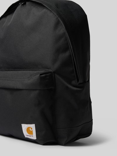 Produktfoto, Rucksack mit Label-Patch Modell 'Jake' von Carhartt Work In Progress, schwarzer Stoff, Reißverschlüsse, glatte Textur, Außenfach, Rechteckform, Kontext: Herren Rucksack, Hauptfach mit Zweiwege-Reißverschluss, verstellbare Schulterriemen, kurzer Tragehenkel, Innenfach aus Mesh, 40x45x14 cm, Schulterriemen 68 cm.