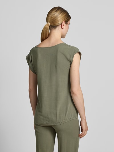 Frauenmodel trägt Regular Fit Bluse aus Viskose-Mix Modell 'Connie' von ZABAIONE in Oliv, glatte Textur, Kurzärmelig, Rückenlänge 60 cm, Ganzkörperansicht Rückansicht.