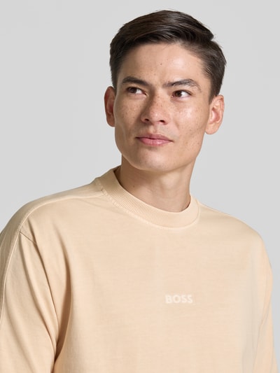 Männermodel trägt Relaxed Fit T-Shirt aus reiner Baumwolle Modell 'TE_TILE' von BOSS Orange in Beige, unifarben, Rundhals, Label-Stitching, Nahaufnahme Oberkörper.