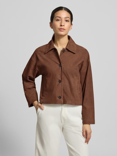 Modelka kobieca nosi Regular Fit Jacke aus echtem Lammvelours mit Umlegekragen od Windsor, brązowy kolor, z guzikami i kieszeniami, krój regular fit, widok całej sylwetki z przodu.