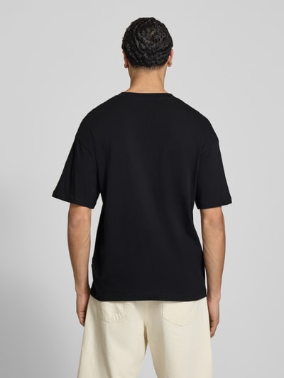 Männermodel trägt schwarzes T-Shirt mit Rundhalsausschnitt von Jack & Jones aus reiner Baumwolle, Regular-Fit, Rückenlänge 70 cm, Ganzkörperansicht Rückansicht.