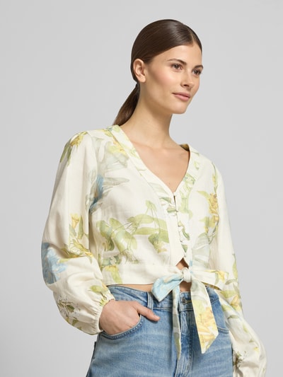 Frauenmodel trägt Cropped Bluse aus Leinen-Viskose-Mix Modell 'SHIRLEY' von Guess mit Blumenmuster in Creme, Knopfleiste, V-Ausschnitt, Nahaufnahme Oberkörper.