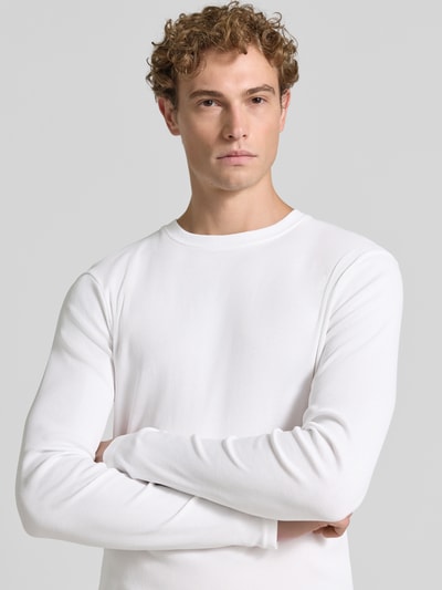 Männermodel trägt weißes Slim Fit Longsleeve aus reiner Baumwolle Modell 'Enil' von DRYKORN mit Strukturmuster, Nahaufnahme Oberkörper.