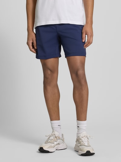 Męski model nosi Regular Fit Shorts mit Logo-Print od Fabletics, materiał elastyczny, granatowy kolor, szerokość w rozmiarze M: 39 cm, całkowity widok z przodu.