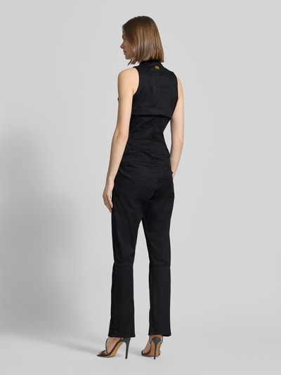 Vrouwenmodel draagt zwarte jumpsuit met ritssluiting model 'Lynn' van G-Star Raw, mix van katoen en elastaan, regular fit, rugaanzicht. Context: dames jumpsuit, opstaande kraag, ruglengte maat S 45 cm, borstwijdte 29 cm, totale lengte 148 cm, binnenbeenlengte 76 cm.