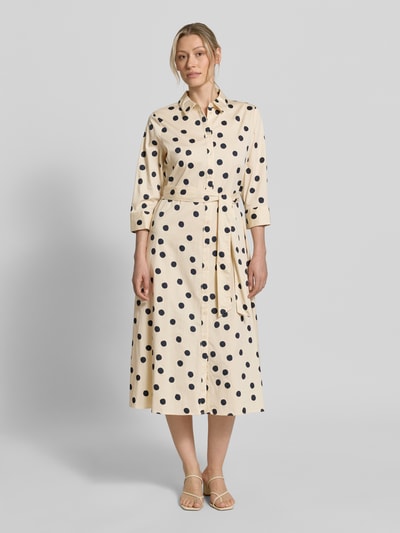 Frauenmodel trägt Regular Fit Blusenkleid aus Baumwoll-Mix von s.Oliver BLACK LABEL, Optik:Allover-Muster mit Polka-Dots, Midi-Länge, Hemdblusenkragen, Knopfleiste, Taillengürtel, Langarm mit Ballonärmel, Manschette, seitliche Eingrifftaschen, cremige Grundfarbe mit schwarzen Punkten, glatte Stoffstruktur, Ganzkörperansicht von vorne.