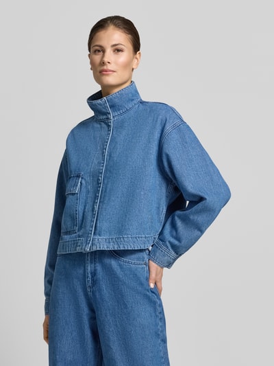 Vrouwenmodel draagt Cropped Denim-Jacke - curated by Tinvcb van SIC, los vallend, cropped model, denimlook, opstaande kraag, klepzak, blauw, textuur stevig katoen, lengte 51 cm, schouderbreedte 52 cm, borstwijdte 60 cm, mouwlengte 55 cm, frontaal totaalbeeld.