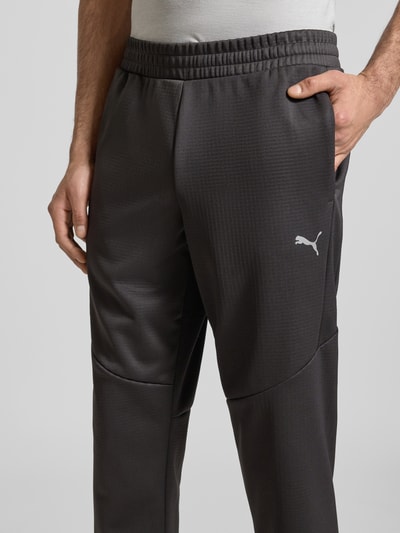 Männermodel trägt Sweatpants mit elastischem Bund von PUMA PERFORMANCE, Label-Print, französische Eingrifftaschen, Nahaufnahme Oberkörper.