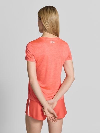Vrouwenmodel draagt T-Shirt met V-Ausschnitt und Logo van Under Armour in regular fit, koraalrood, detail van logo, ruglengte 61 cm, Ganzkörperansicht Rückansicht.