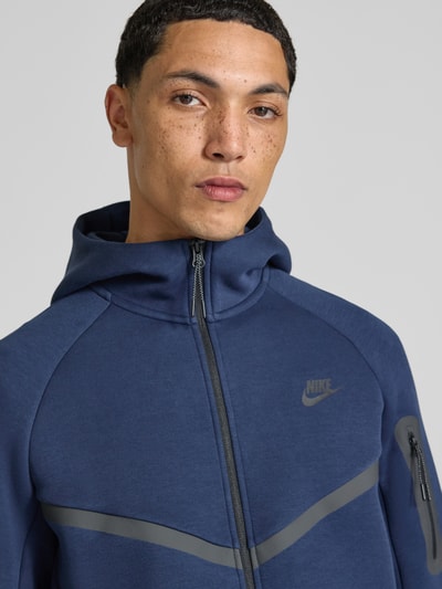 Mężczyzna nosi Regular Fit Sweatjacke aus Baumwoll-Mix von Nike w kolorze granatowym z szarymi detalami, Nahaufnahme Oberkörper.