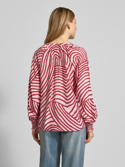 Vrouwenmodel draagt Overhemdblouse met knoopsluiting Model 'BECCA' van Soyaconcept, viscosemix, los model, V-hals, ruglengte maat S 63 cm, mouwlengte maat S 72 cm, abstract rood-wit patroon, achterkant geheel zichtbaar, geheellichaamsaanzicht achteraan.