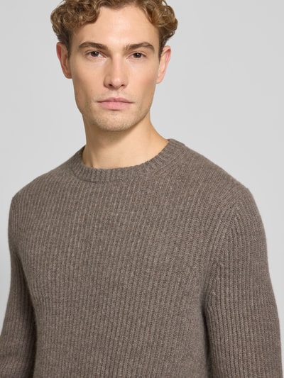 Männermodel trägt Strickpullover aus Kaschmir mit Rundhalsausschnitt von FTC Cashmere in Braun, Grobstrick, Nahaufnahme Oberkörper.