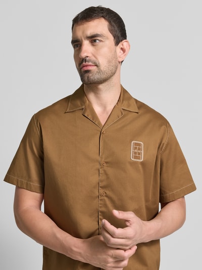 Männermodel trägt Regular fit vrijetijdsoverhemd uit pure katoen van Lacoste in bruin, korte mouwen, Heren. Nahaufnahme Oberkörper.