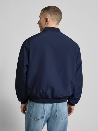 Männermodel trägt dunkelblaue Bomberjacke mit Stehkragen Modell 'CHARGE' von Jack & Jones, Regular-Fit, Rückansicht, glatte Textur, Herren-Bekleidung, Reißverschluss, Rückenlänge 67 cm, Schulterbreite 53 cm, Brustweite 62 cm, Ärmellänge 65 cm. Ganzkörperansicht Rückansicht.