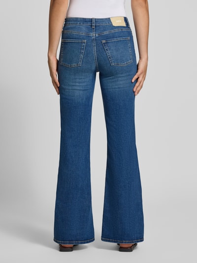 Frauenmodel trägt Flared Jeans mit Knopfverschluss Modell 'ROME' von JJXX, mittelblaue Farbe, 5-Pocket-Design, Baumwoll-Mix mit Stretch-Anteil, Ganzkörperansicht Rückansicht.