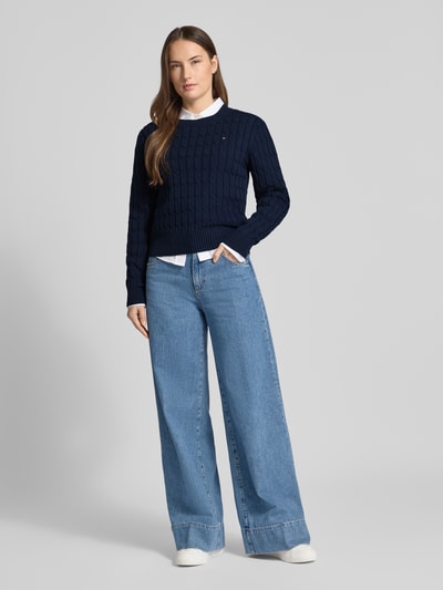 Frauenmodel trägt Slim Fit Strickpullover aus reiner Baumwolle von Tommy Hilfiger in Dunkelblau mit Rundhals, Two Tone, gestreift, Ganzkörperansicht von vorne.