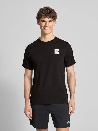 Männermodel trägt schwarzes T-Shirt aus Baumwoll-Mix Modell 'EVOLUTION' von The North Face, Regular Fit, Rundhals, Label-Print, Ganzkörperansicht von vorne.