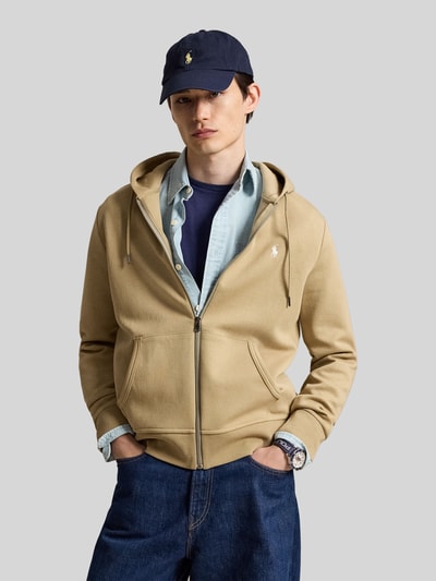 Męski model nosi Regular Fit Sweatjacke aus Baumwoll-Mix od Polo Ralph Lauren, kolor beżowy, kieszenie z przodu, gładka tekstura, Ganzkörperansicht von vorne.