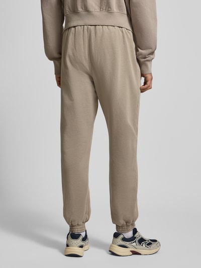 Mannelijk model draagt Sweatpants met elastische tailleband van Pegador, beige katoenmix, losse pasvorm, achterkant, volledige lichaamsweergave.