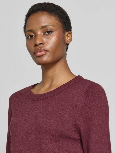 Frauenmodel trägt Strickpullover aus Viskose-Mix von VILA in dunklem Bordeaux, gerippter Rundhalsausschnitt, Nahaufnahme Oberkörper.