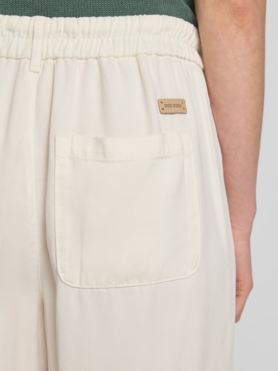 Frauenmodel trägt Straight Fit Stoffhose aus reinem Lyocell Modell 'Maison' von MOS MOSH in Creme mit Tunnelzugbund, Detailaufnahme Rückansicht. Damen Stoffhose mit glatter Textur, Bundweite bei Größe S: 38 cm, Innenbeinlänge 72 cm.