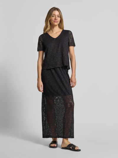 Frauenmodel trägt Regular Fit T-Shirt in Heckel-Optik Modell 'MAYA' von Vero Moda, schwarz, Allover-Muster, V-Ausschnitt, Ganzkörperansicht von vorne.