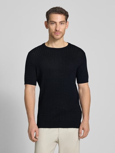 Männermodel trägt Regular Fit T-Shirt aus reiner Baumwolle Modell 'ADRIAN-TC' von Strellson, schwarze Strickoptik mit Zopfmuster, Rundhals, Langarm, Ganzkörperansicht von vorne.